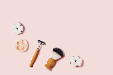 Bathroom accessories on pink background. Sponges, cotton flowers, shaving brush and razor. Flat lay, top view.の写真素材
