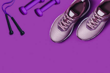 Sports equipment for gymnastics. Purple background with a place for text. Sneakers, dumbbells and skipping rope.の写真素材