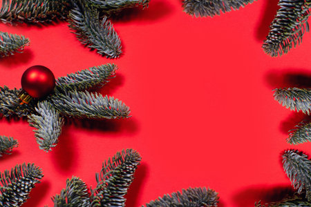 Photo with red Christmas balls on fir branches. Color background with space for text in center.の写真素材