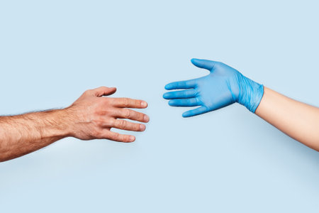 The mens hand and the womans hand in the latex glove are drawn to each other. The photo symbolizes...