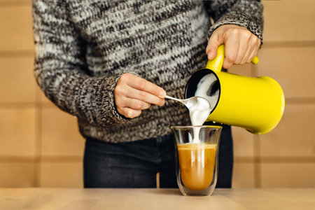 Woman at home in her rustic kitchen prepares tasty cappuccino with special machine.の写真素材