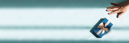 Web banner with womans hand reaching for box with gift inside in sunlight.の写真素材
