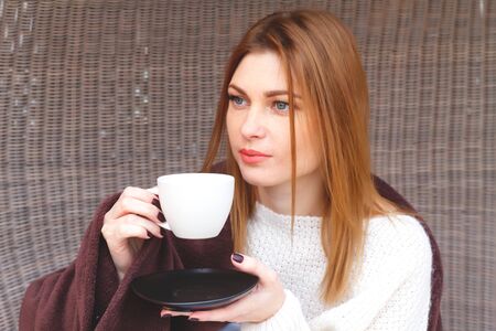 beautiful woman drinks hot cofee wrapped in a plaidの写真素材