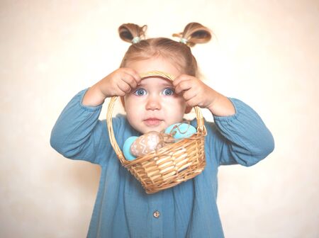 blue-eyed blonde girl with a basket of Easter eggs in a vintage dress.の写真素材