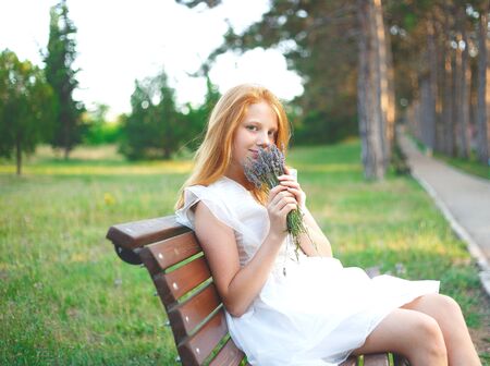 red-haired girl in a white dress walks in the park.の写真素材