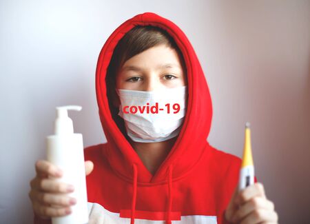a boy in a red hood in a medical mask with a disinfector and a thermometer. inscription coronavirus...