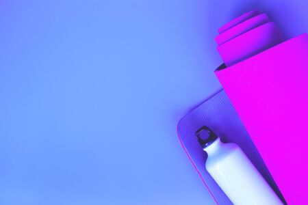 Bright purple yoga mat and bottle of water. flat layの写真素材