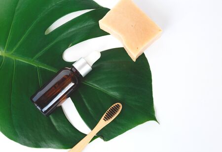 The concept of zero waste. bamboo toothbrush, solid shampoo and serum on a manstera sheet. flat layの写真素材