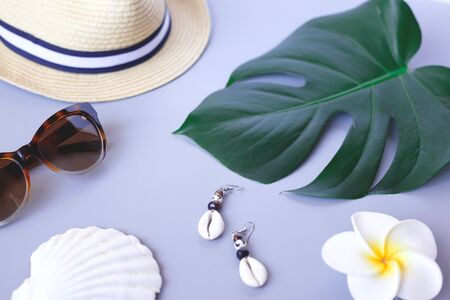 Travel accessories: hat, monstera branch, flover, sunglass on a grey background.の写真素材