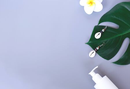 Travel accessories: monstera branch, flover, sunscreen on a grey background. flat layの写真素材