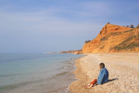 girl sitting on the sand by the sea. spring nature.の写真素材
