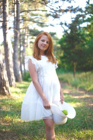 red-haired girl in a white dress with a green apple in her hat.の写真素材