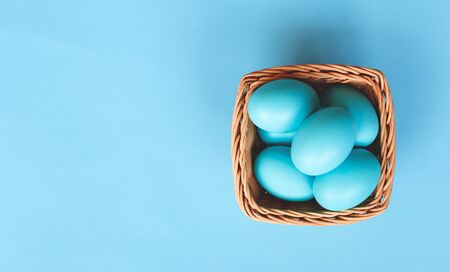 wicker basket with easter eggs on a blue background.の写真素材