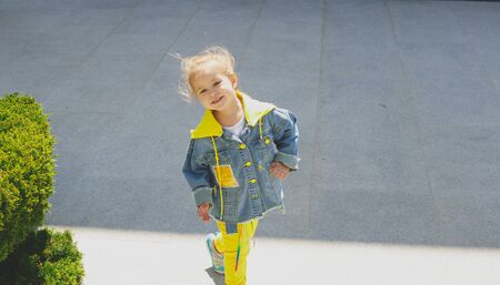 Little cute blonde blue-eyed girl smiles on a walk.の写真素材