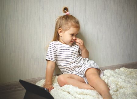 little girl at home watching tablet computer. home schooling, distance learning.の写真素材