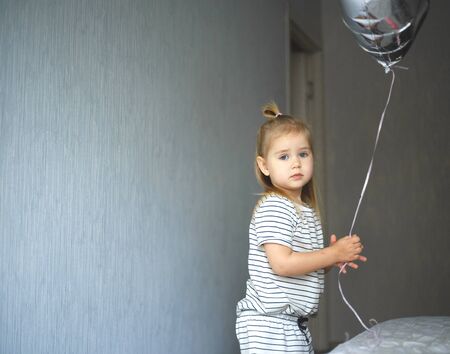 little blue-eyed girl with a silver balloon.の写真素材