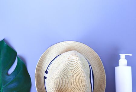 Travel accessories: monstera branch, hat, sunscreen on a grey background. flat lay