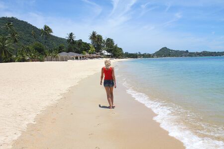 happy woman walks barefoot on the sand by the sea.の写真素材