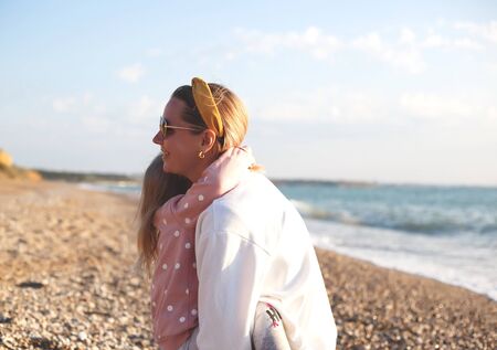 mom and daughter hug and kiss on the beach at sunset.の写真素材