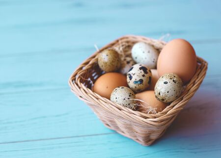 wicker basket with quail and compartment eggs on a gray background. happy easter.