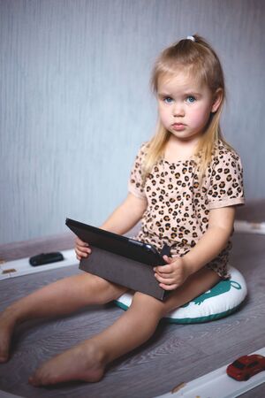 little girl at home watching tablet computer. home schooling, distance learning.の写真素材