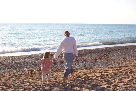 mom and daughter are playing on the sandy beach.の写真素材