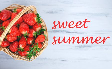 wicker basket with fresh strawberries on a wooden background.の写真素材