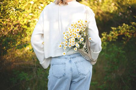 woman with a bouquet of daisies in an eco friendly net bag.の写真素材