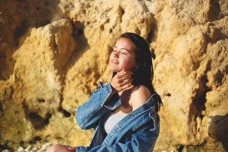portrait of a woman in a denim jacket on a background of yellow rock.の写真素材