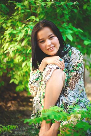 portrait of a beautiful smiling brunette on a background of greenery.の写真素材