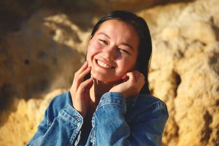 portrait of a woman in a denim jacket on a background of yellow rock.の写真素材
