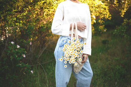 woman with a bouquet of daisies in an eco friendly net bag.の写真素材