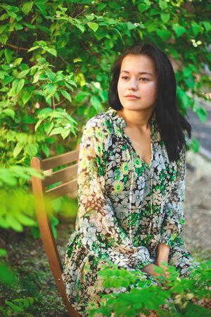 portrait of a beautiful smiling brunette on a background of greenery.の写真素材