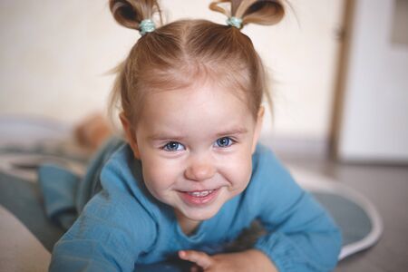 blue-eyed blonde girl in a vintage blue dress smiling.の写真素材