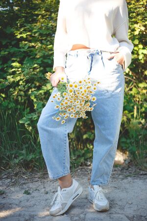 woman with a bouquet of daisies in an eco friendly net bag.の写真素材