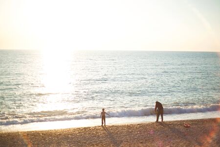 family walks on the seashore at sunset.の写真素材