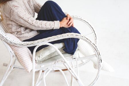 girl in a cozy white vintage chair in a knitted light socks and sweater.の写真素材