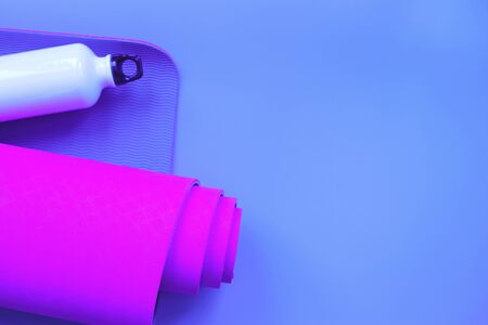 Bright purple yoga mat and bottle of water. flat layの写真素材