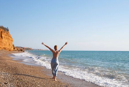 happy woman walks barefoot on the sand by the sea.の写真素材