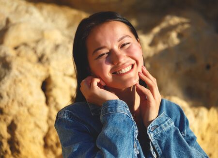 portrait of a woman in a denim jacket on a background of yellow rock.の写真素材