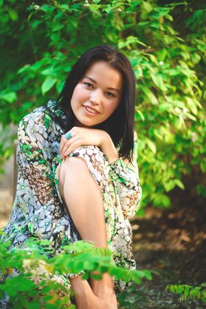 portrait of a beautiful smiling brunette on a background of greenery.の写真素材