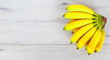bright fresh mini bananas on gray wooden background.の写真素材