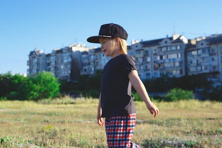 little girl walks on the lawn on the background of houses.の写真素材