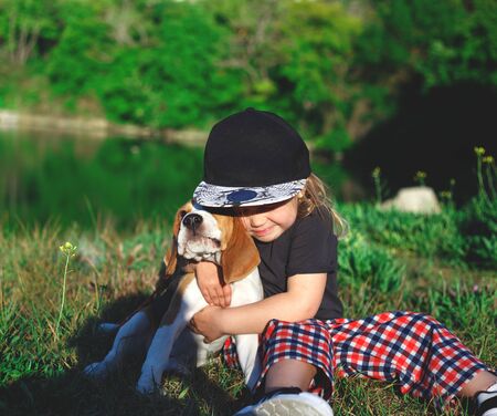 little girl hugs a cute beagle puppy.の写真素材