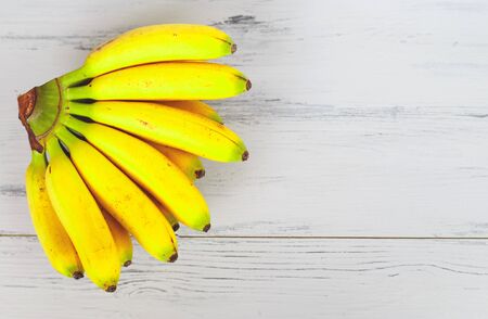 bright fresh mini bananas on gray wooden background.の写真素材