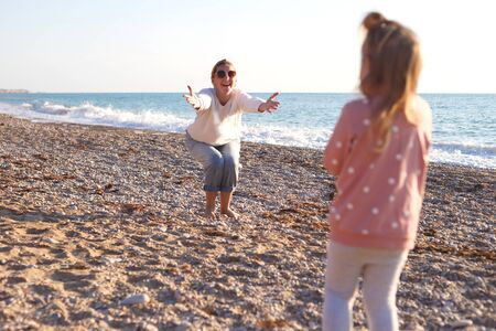 mom and daughter are playing on the sandy beach.の写真素材