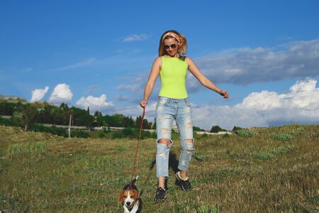 young woman on a walk with a beagle puppy.の写真素材