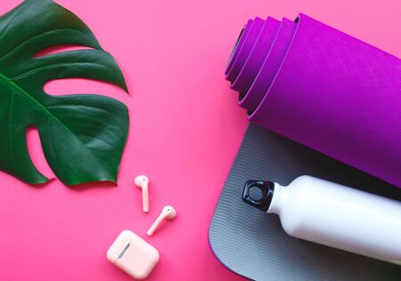purple yoga mat, water bottle and headphones on a pink background.の写真素材