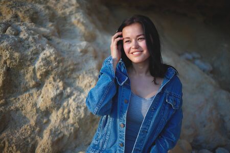 portrait of a woman in a denim jacket on a background of yellow rock.の写真素材