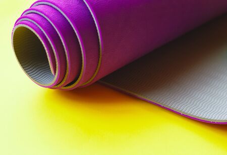 Bright purple yoga mat on a yellow background.の写真素材